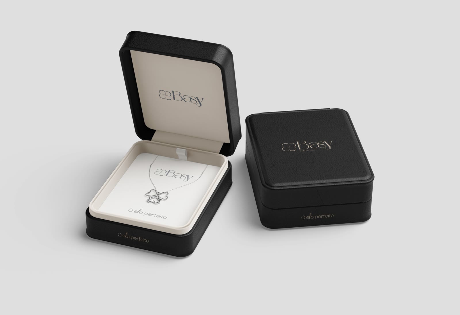 Caixas de joia pretas com a marca Basy e um colar com o trevo