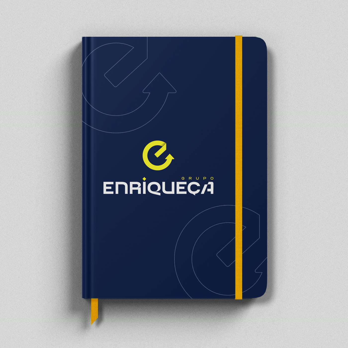 Caderno azul marinho com o logo do Grupo Enriqueça e elástico amarelo